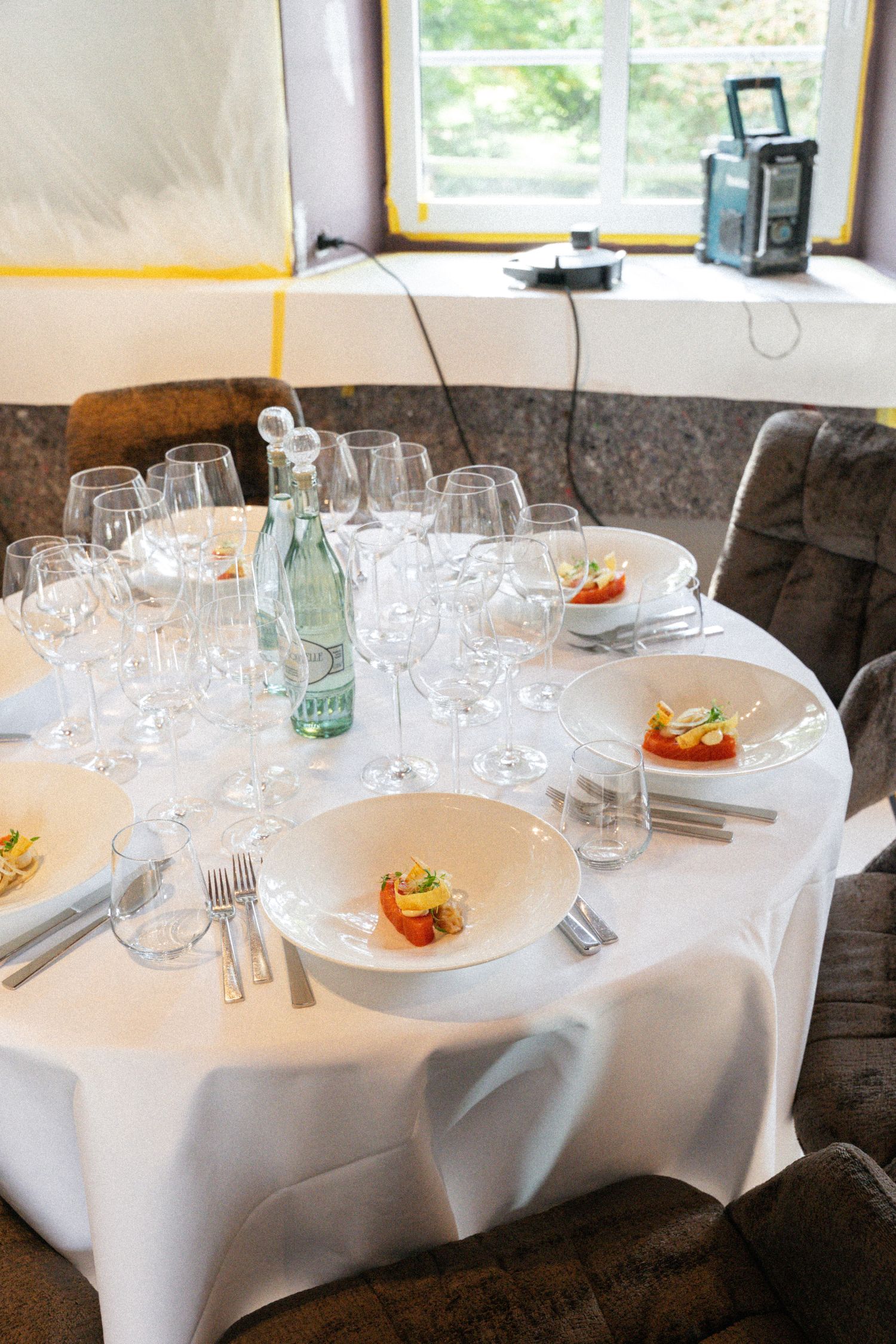 Tisch im Restaurant mit Gläsern, Wasserflasche, Teller mit einer Vorspeise