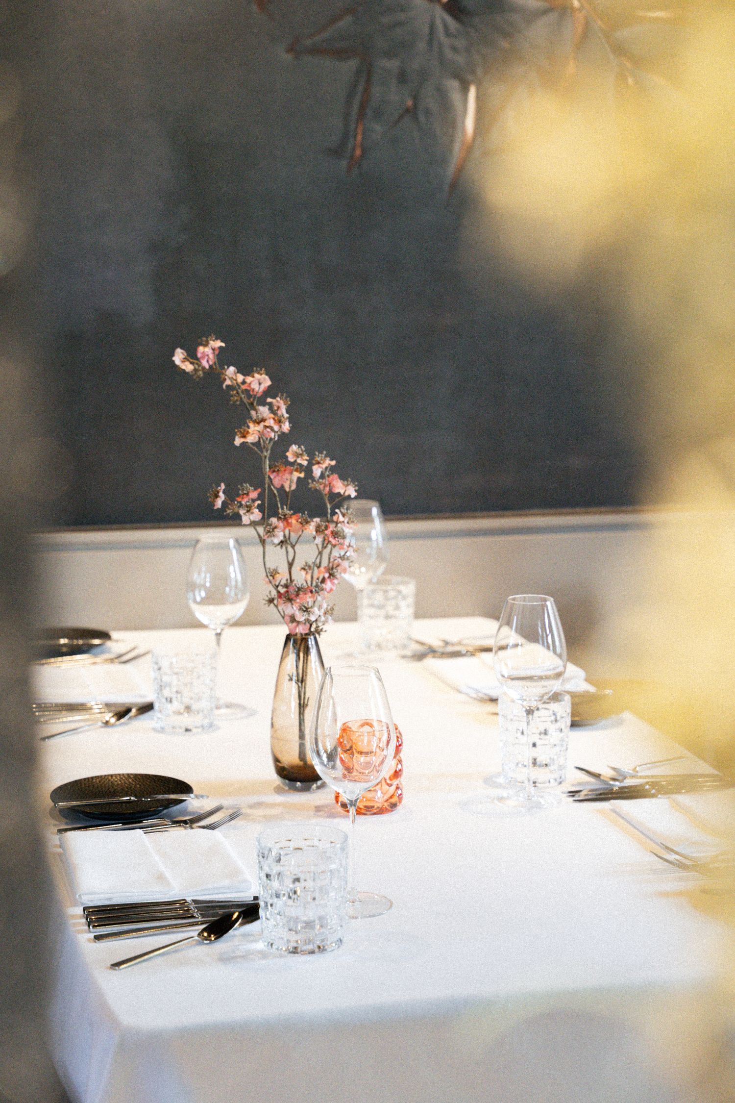 Eingedeckter Tisch im Restaurant mit Deko und blauer Tapete im Hintergrund