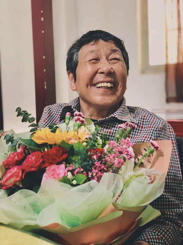 man in red and white checkered dress shirt holding bouquet of flowers