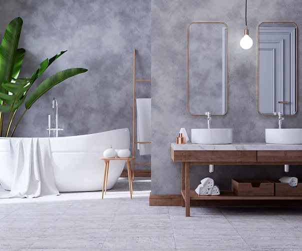 Modernes Badezimmer mit freistehender Badewanne, zwei Waschbecken auf Holzunterschrank, großen Pflanzen und grauen Wänden.