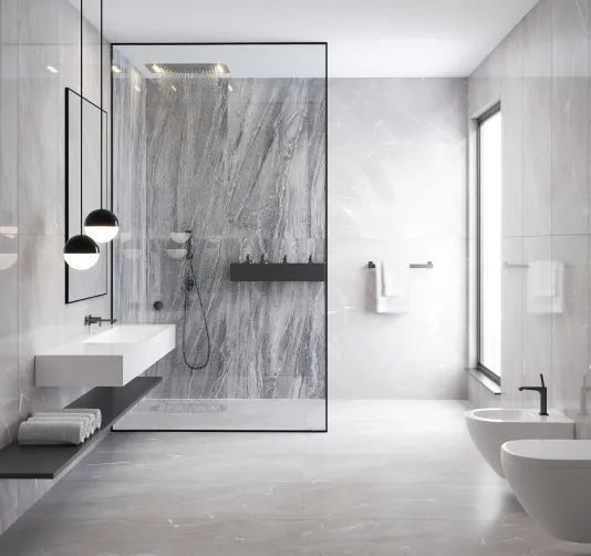 Modernes Badezimmer mit grauen Marmorfliesen, freistehender Dusche mit Glaswand, zwei Hängeleuchten, Waschbecken mit Ablagefach und Toilette mit Bidet.