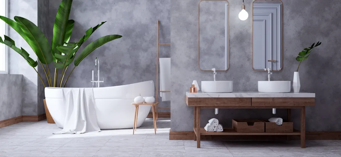 Modernes Badezimmer mit freistehender Badewanne, großen grünen Pflanzen, Doppelwaschbecken mit zwei Spiegeln und grauen Wänden.