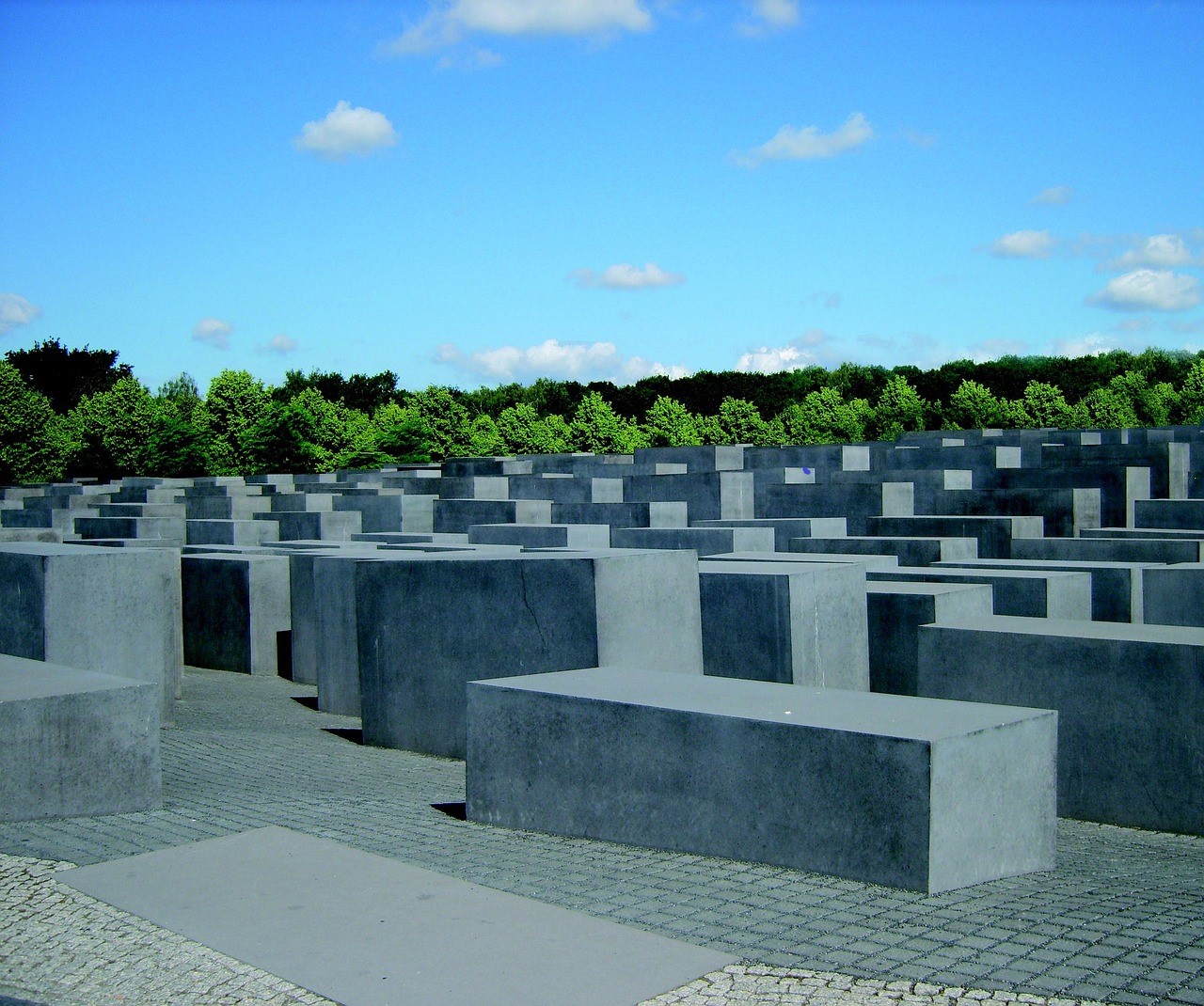 Das Holocaust-Mahnmal in Berlin mit grünen Bäumen im Hintergrund