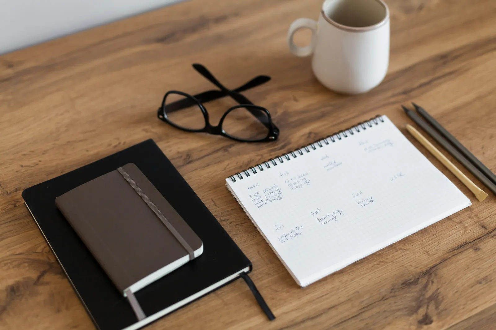 Notepad, pen, reading glasses and a cup of coffee on a table
