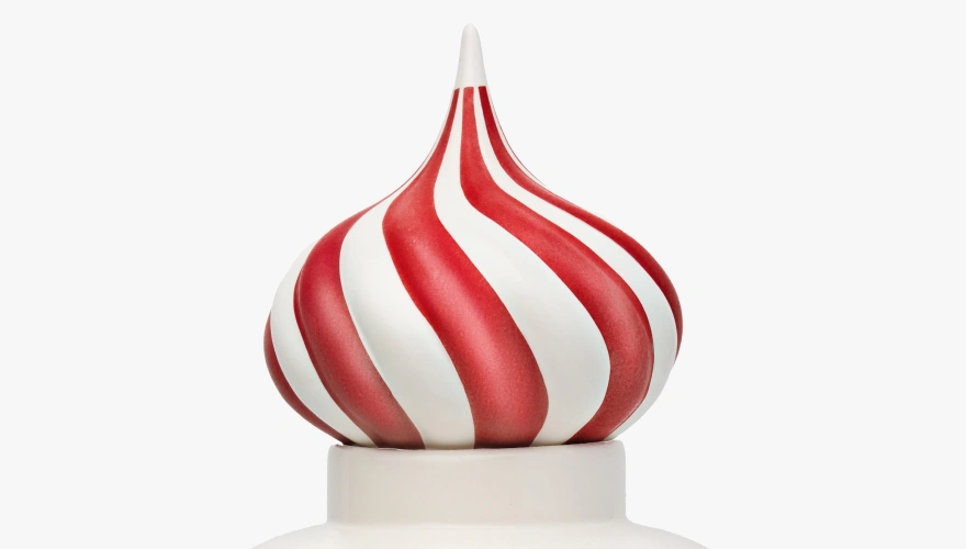 Close-up of a white and red striped swirl topping resembling a peppermint candy on a white container.