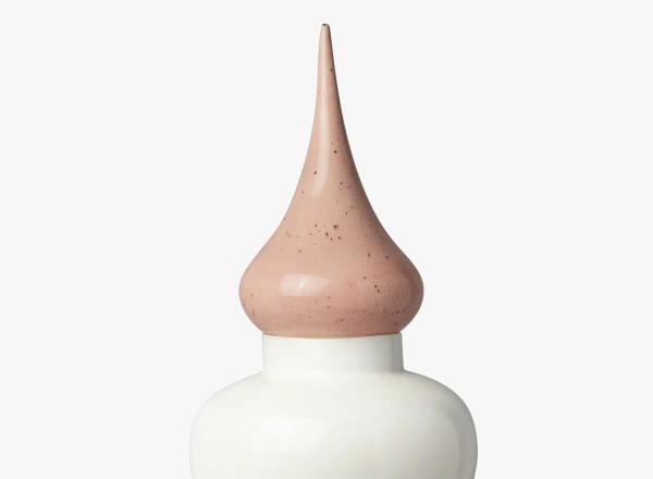 Close-up of a white bottle with a tall, pointed, pink speckled cap.