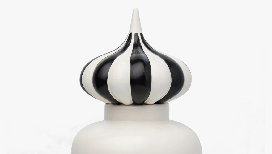 Close-up of a decorative ceramic object with a black and white striped onion-shaped top.