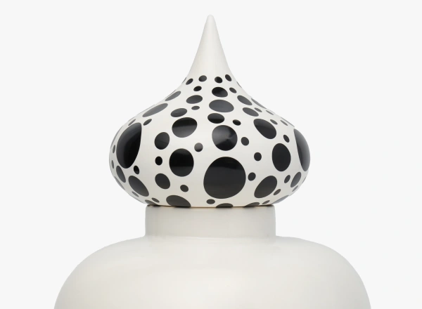 White ceramic jar with a pointed lid decorated with various sizes of black polka dots.