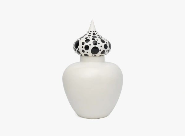 White ceramic jar with a rounded body and a pointed lid decorated with black polka dots of varying sizes.