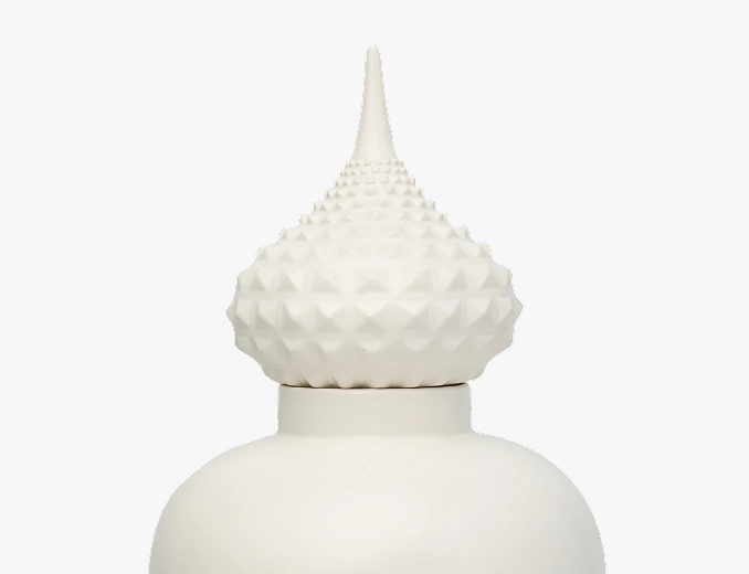 Close-up of a white ceramic jar lid with a pointed, textured finial.