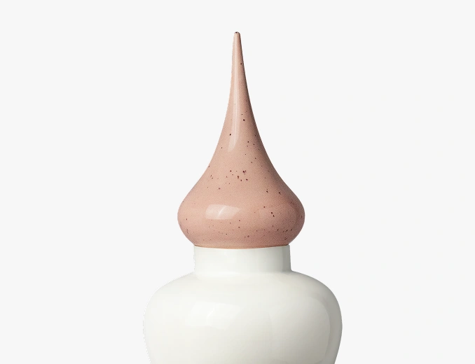White ceramic bottle with a tall, pointed, speckled beige cap.