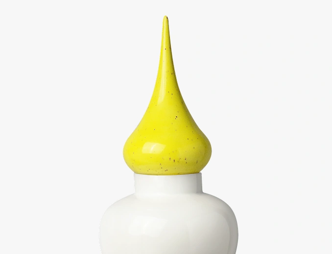 Close-up of a white ceramic container with a glossy yellow pointed lid.