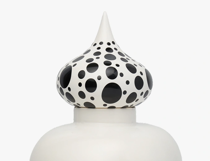 Close-up of a white ceramic lid with a pointed top featuring black polka dots of various sizes.