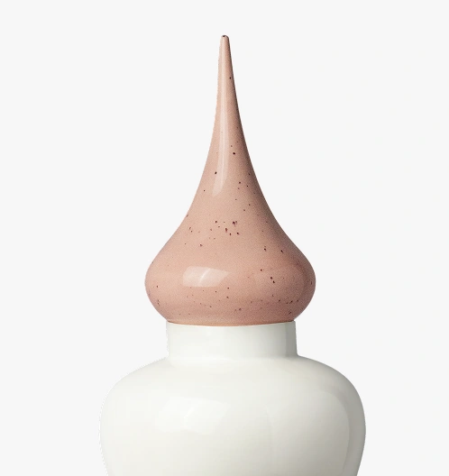 Close-up of a white ceramic bottle with a tall, pointed, speckled beige stopper.