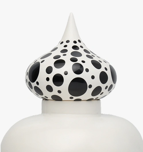 Close-up of a white ceramic bottle stopper with a pointed top and black polka dots of varying sizes.