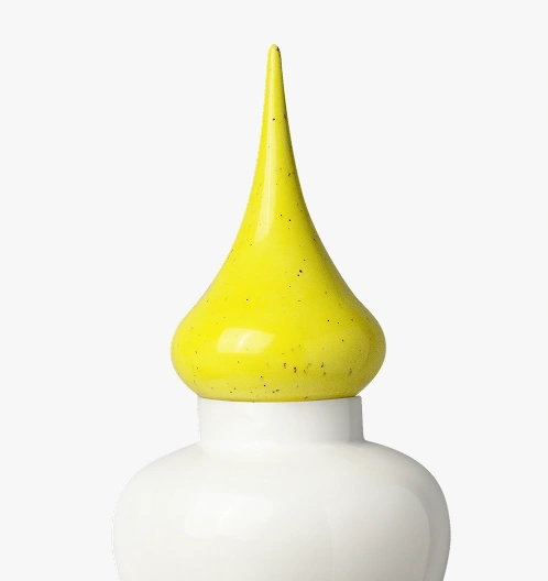 White jar with a tall, pointed yellow lid that has a bulbous base.