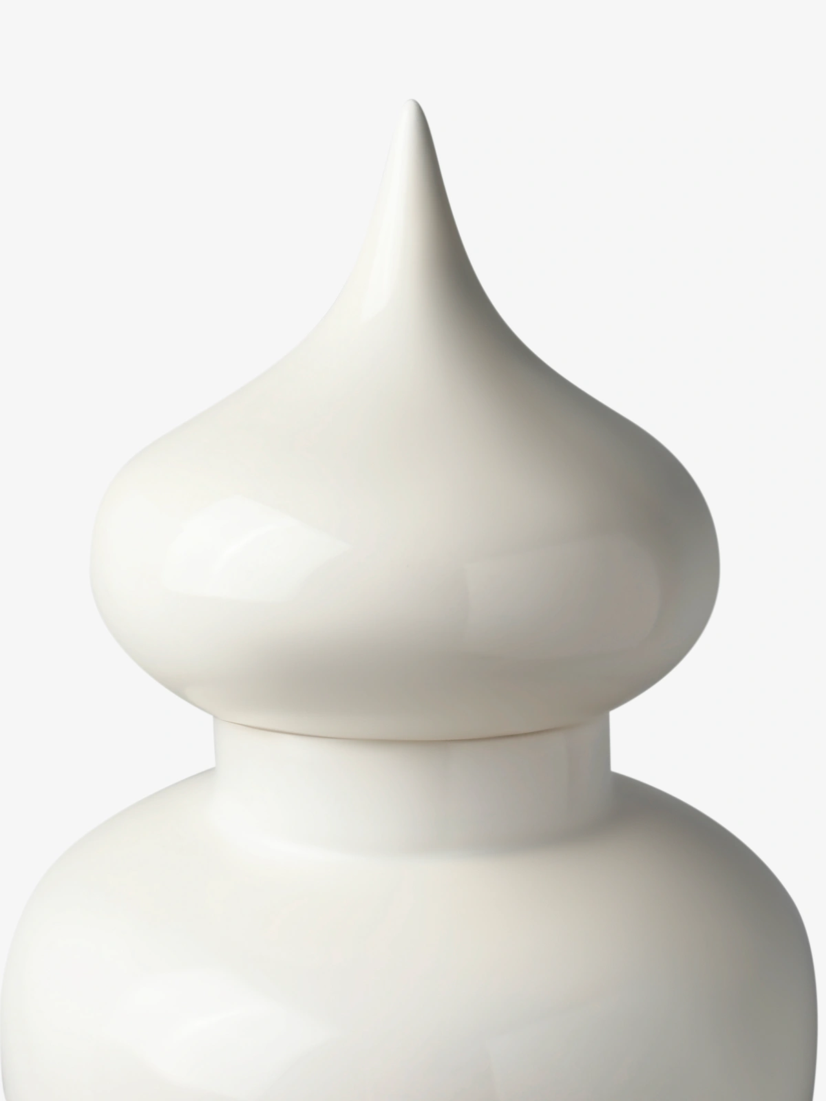 Glossy white ceramic vase with a rounded body and a pointed lid.