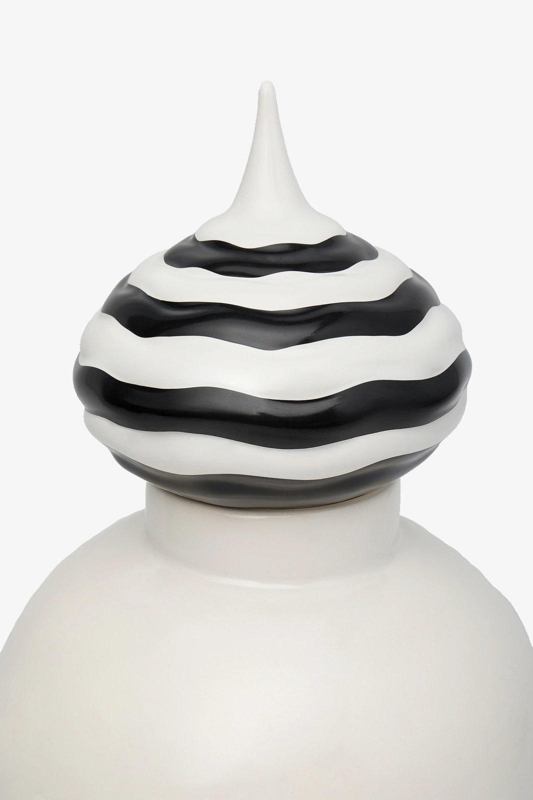 Close-up of a white bottle with a decorative lid featuring wavy black and white stripes and a pointed top.