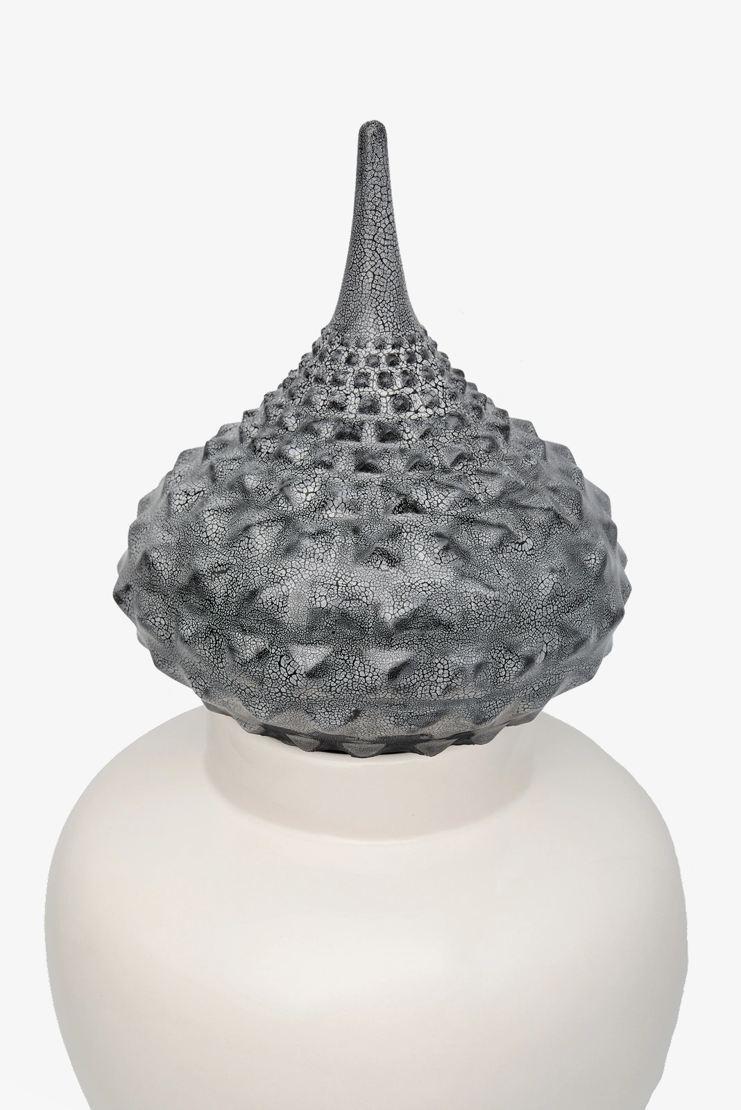 White ceramic jar with a textured, spiked gray lid featuring a tall pointed top.