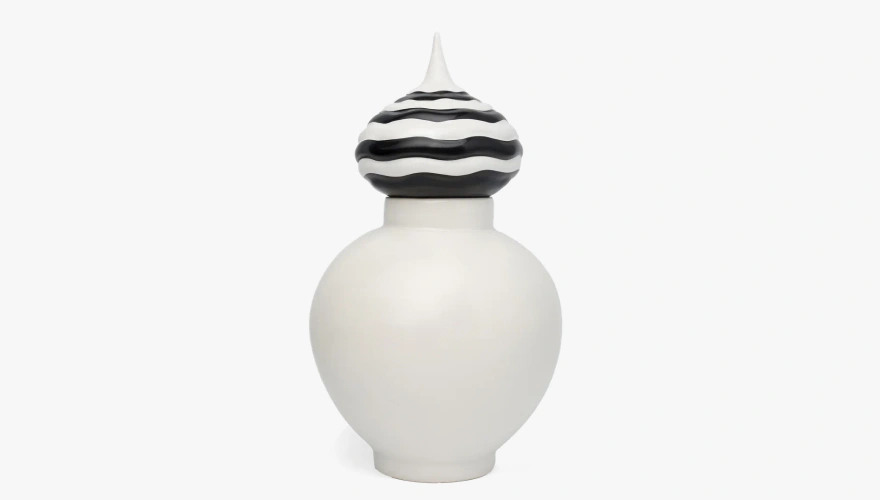 White ceramic vase with a bulbous body and a black-and-white striped wavy lid.