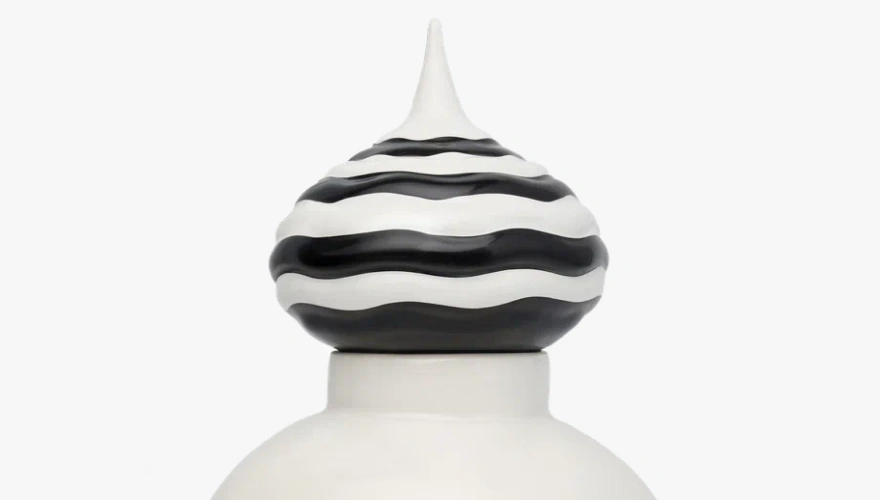Top detail of a white ceramic container lid with black and white wavy striped rounded handle and pointed tip.