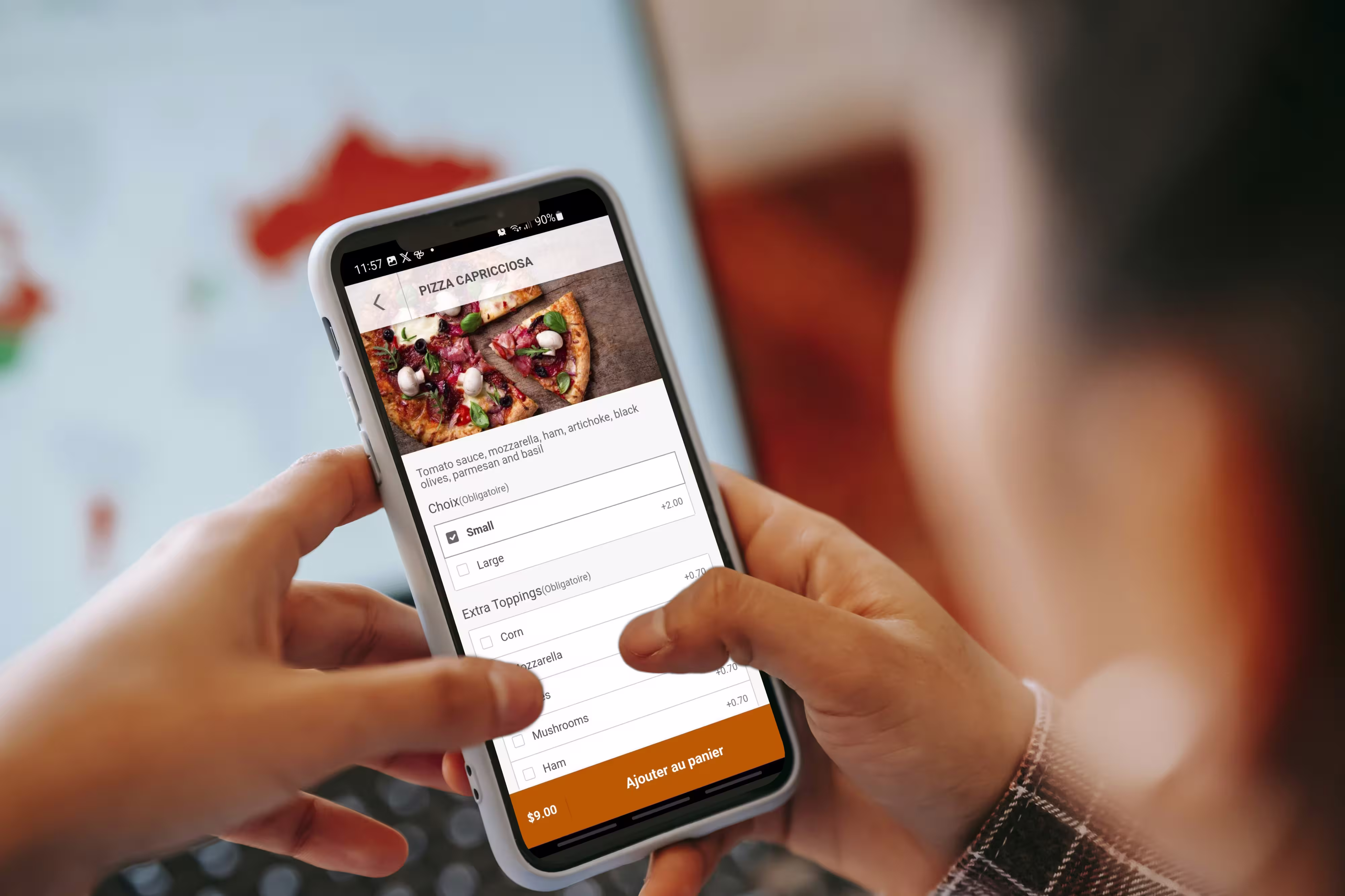 Personne utilisant un smartphone pour commander une pizza capricciosa avec options de taille et garnitures supplémentaires.