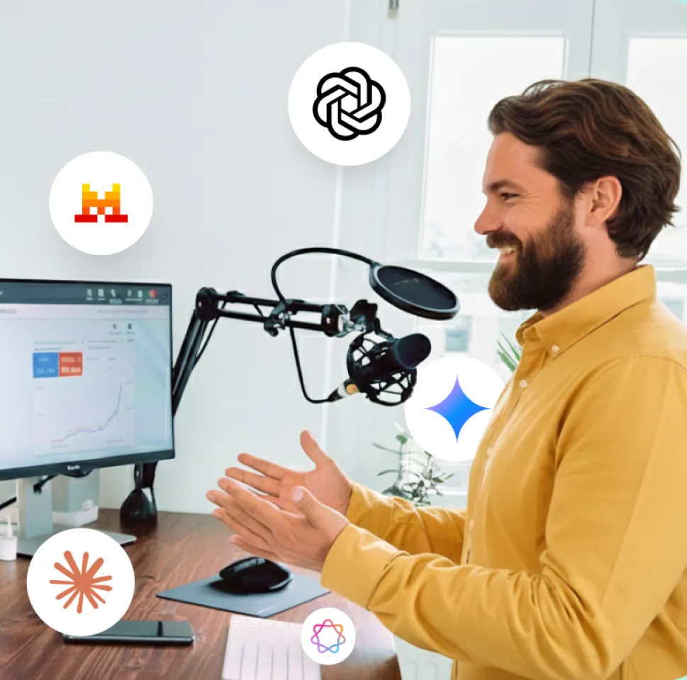 Un homme barbu en chemise jaune discute devant un microphone de podcast avec un écran d'ordinateur affichant un graphique en arrière-plan.