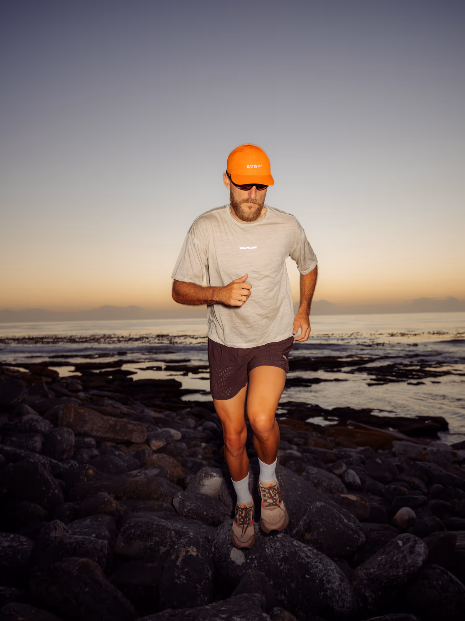 Man running at sunset on a rocky beach 