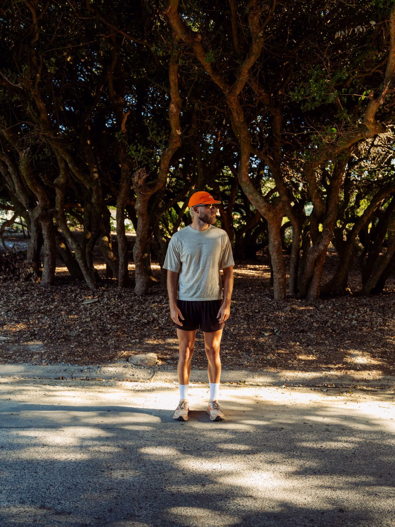 Man stood posing for camera under trees on the road