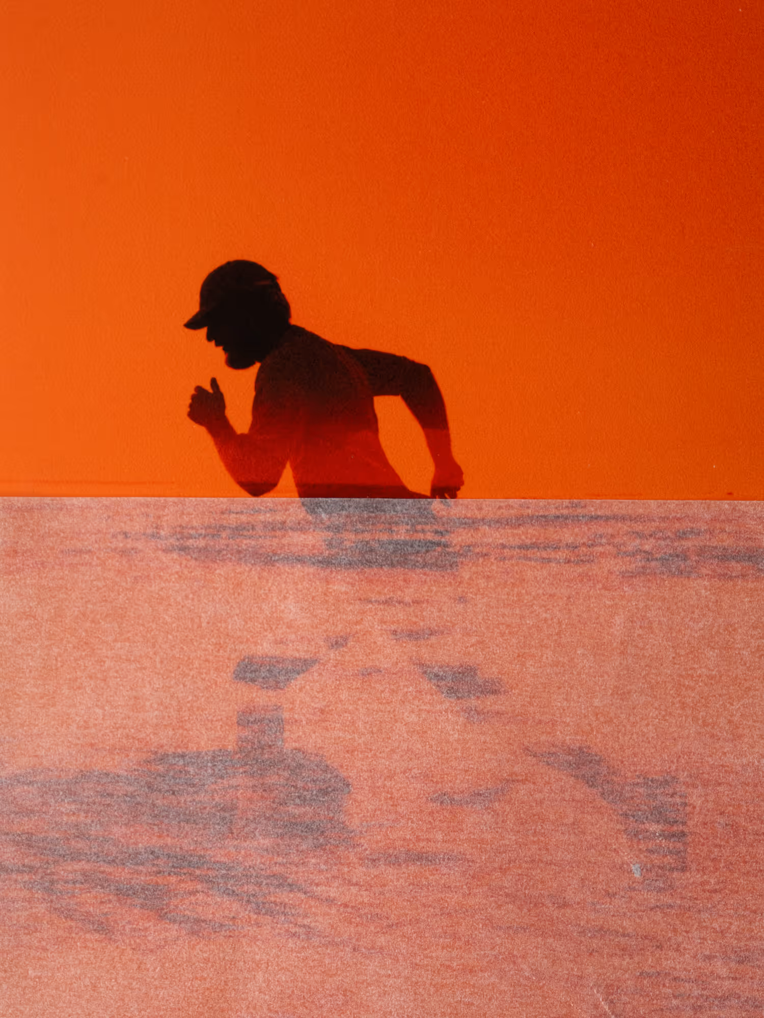 Orange filtered image of a shadow of a man running 