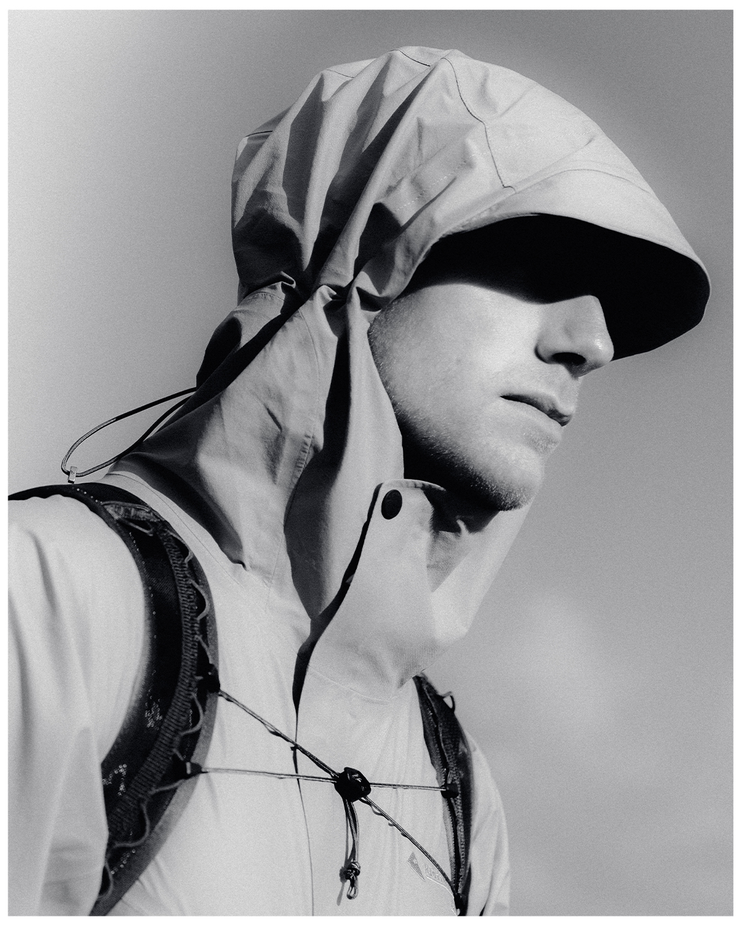Black and white side profile portrait of man with coat hood up 
