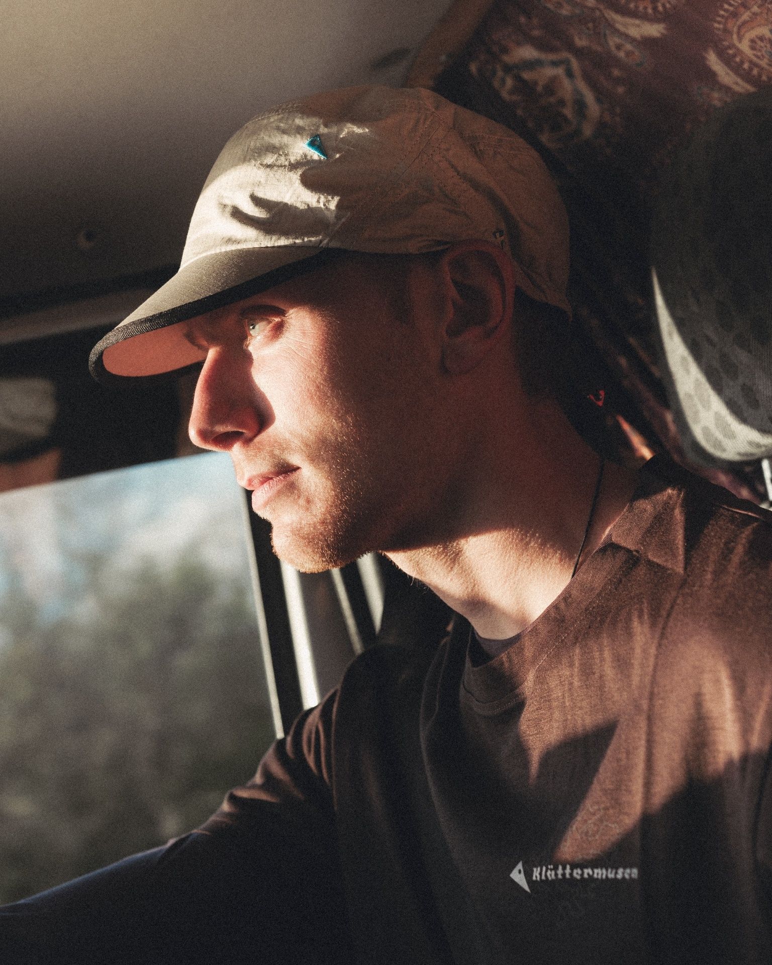 Side profile portrait of man with cap driving in car