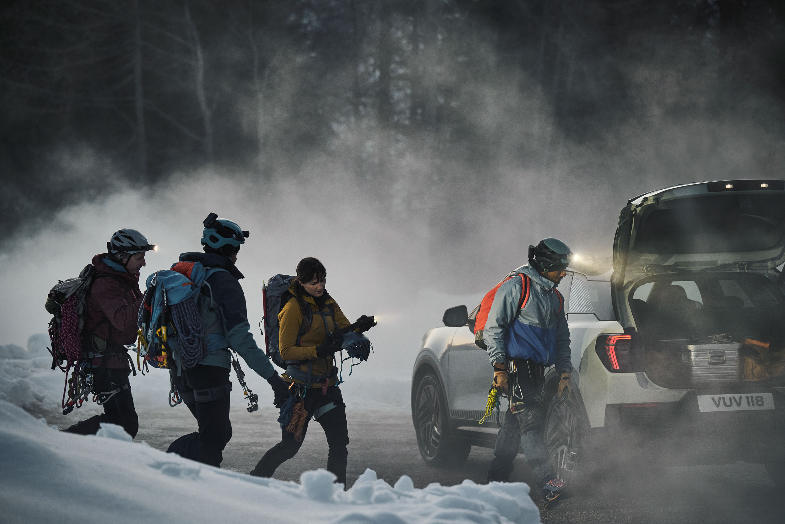 People walking by a car in mountains