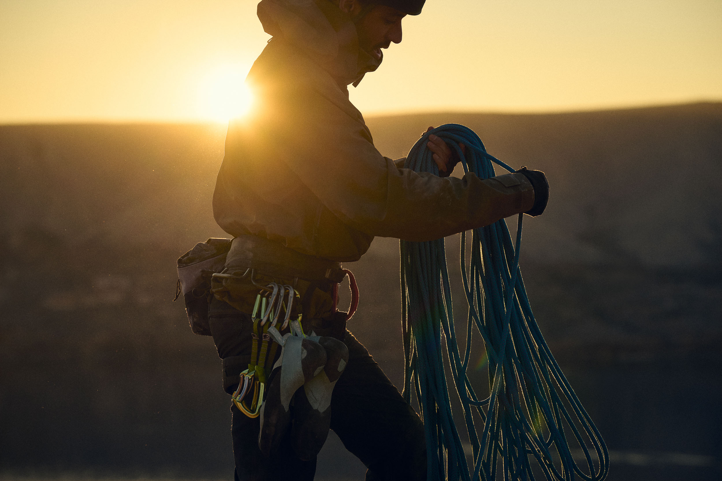 Climber holding equipment at sunset