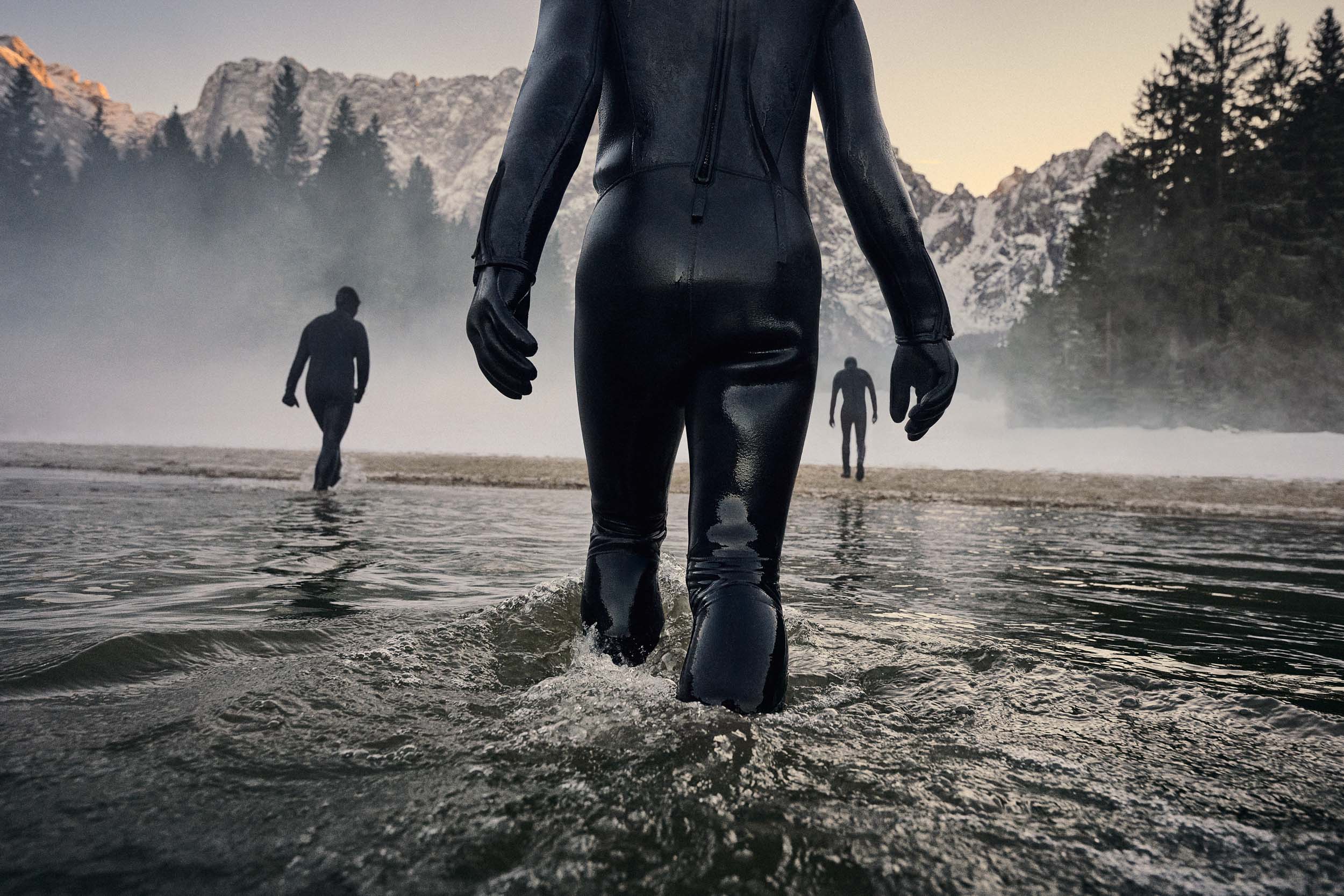 Three people entering water