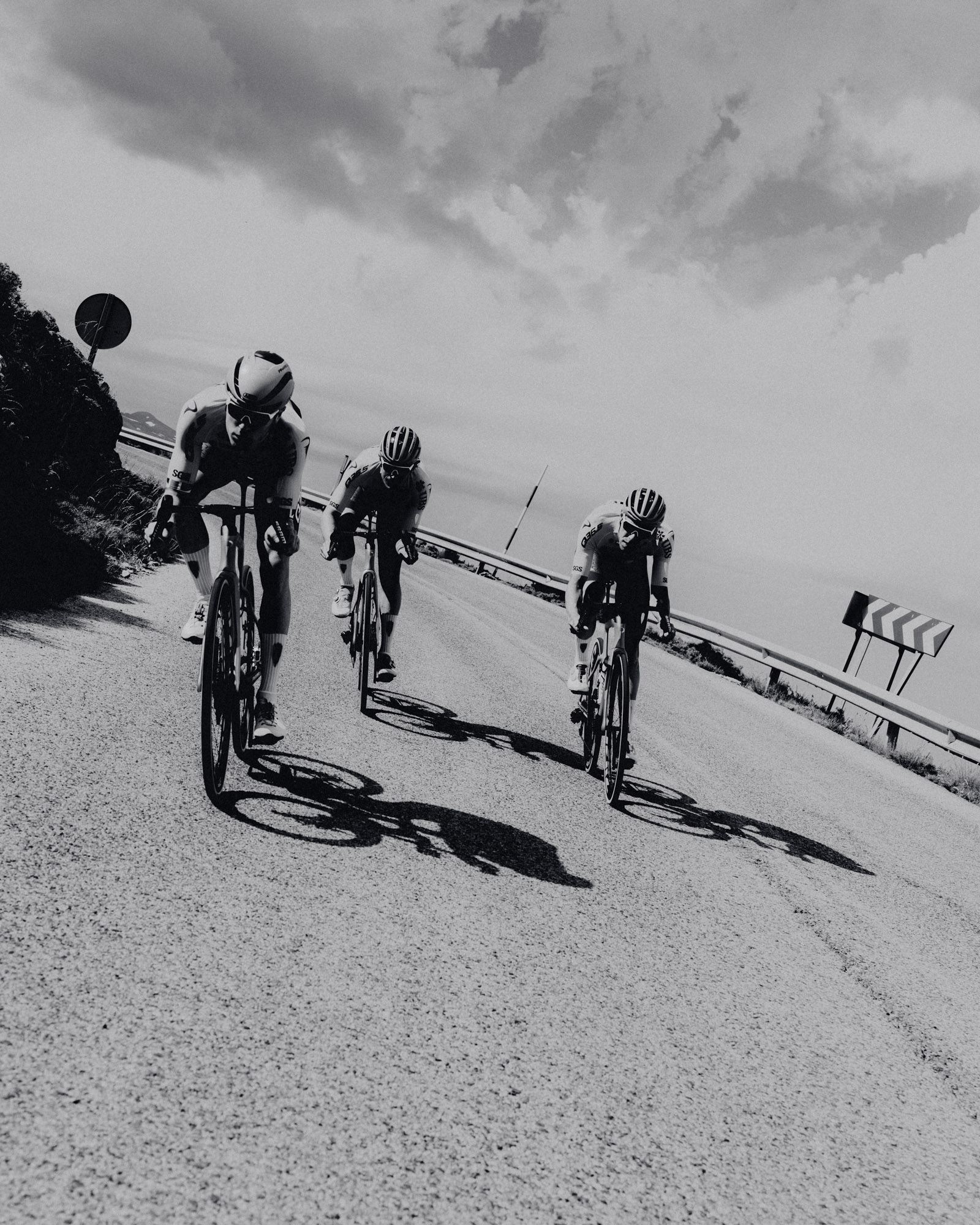 Three men cycling in black and white