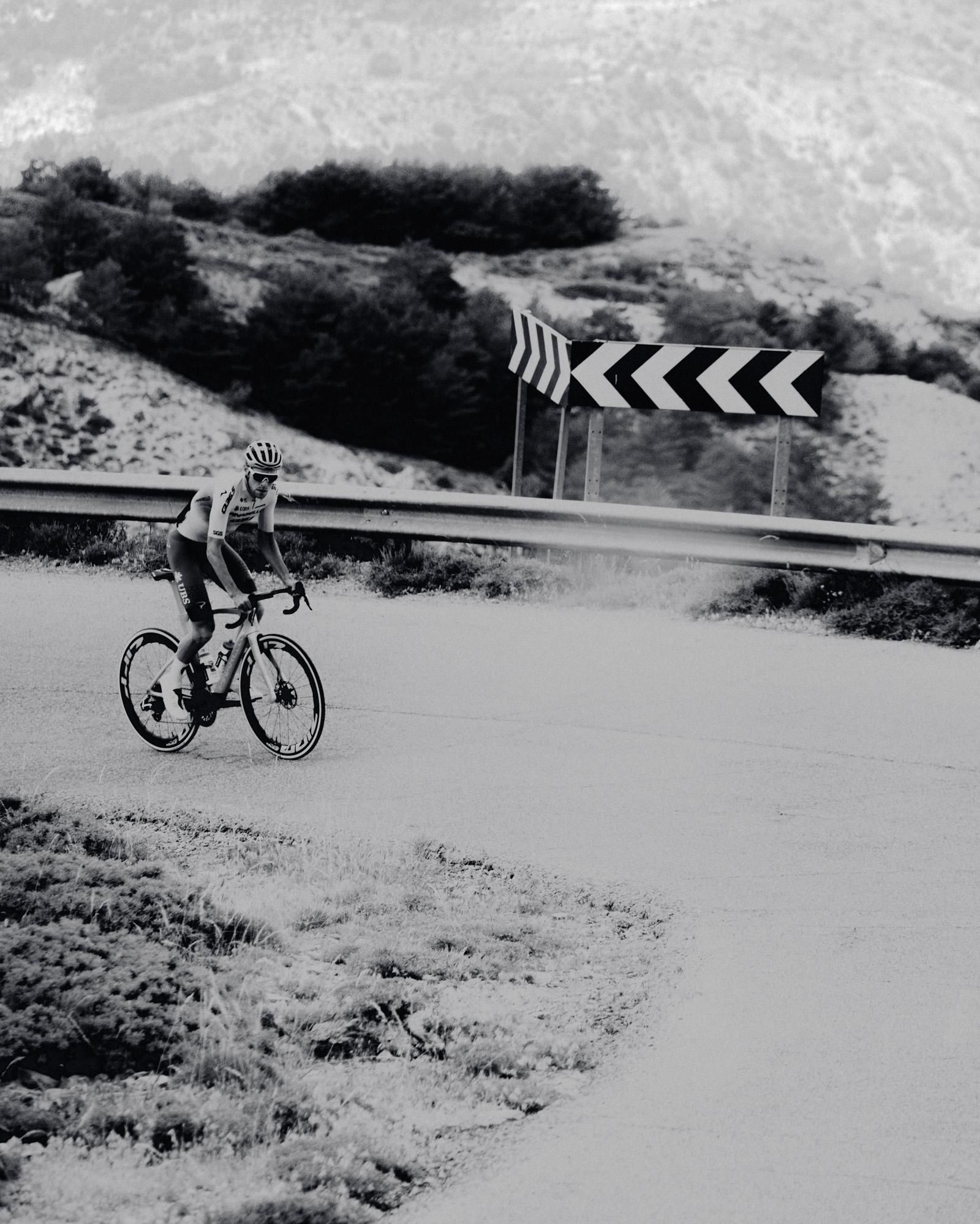 Black and white image of man cycling on road