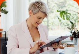 Woman in a pink blazer reviewing her report on a tablet