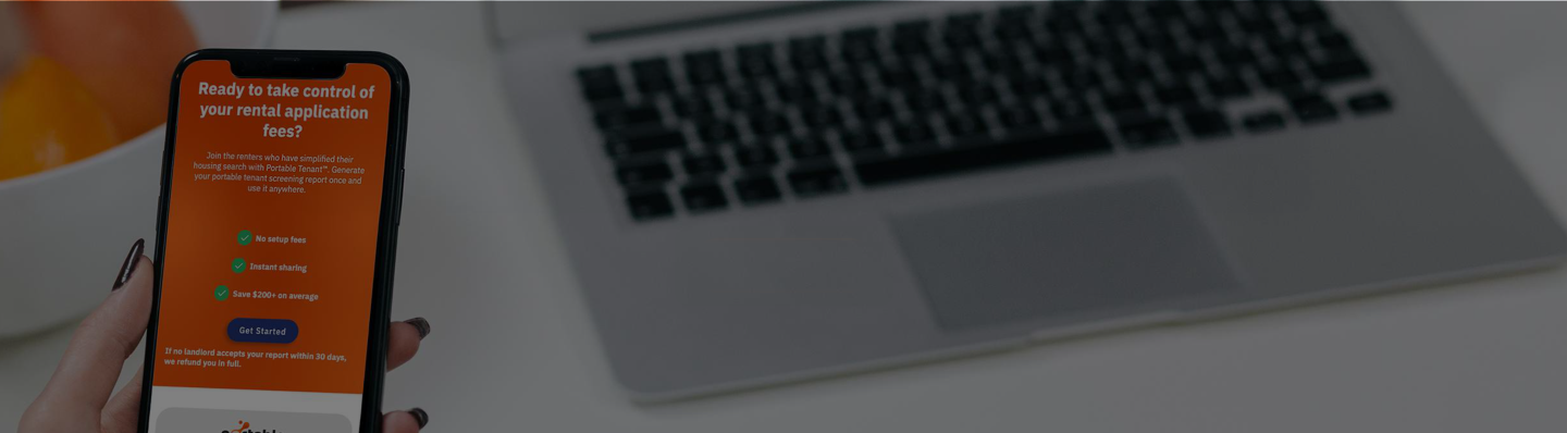 Renter reviewing a Portable Tenant report on a phone beside a laptop