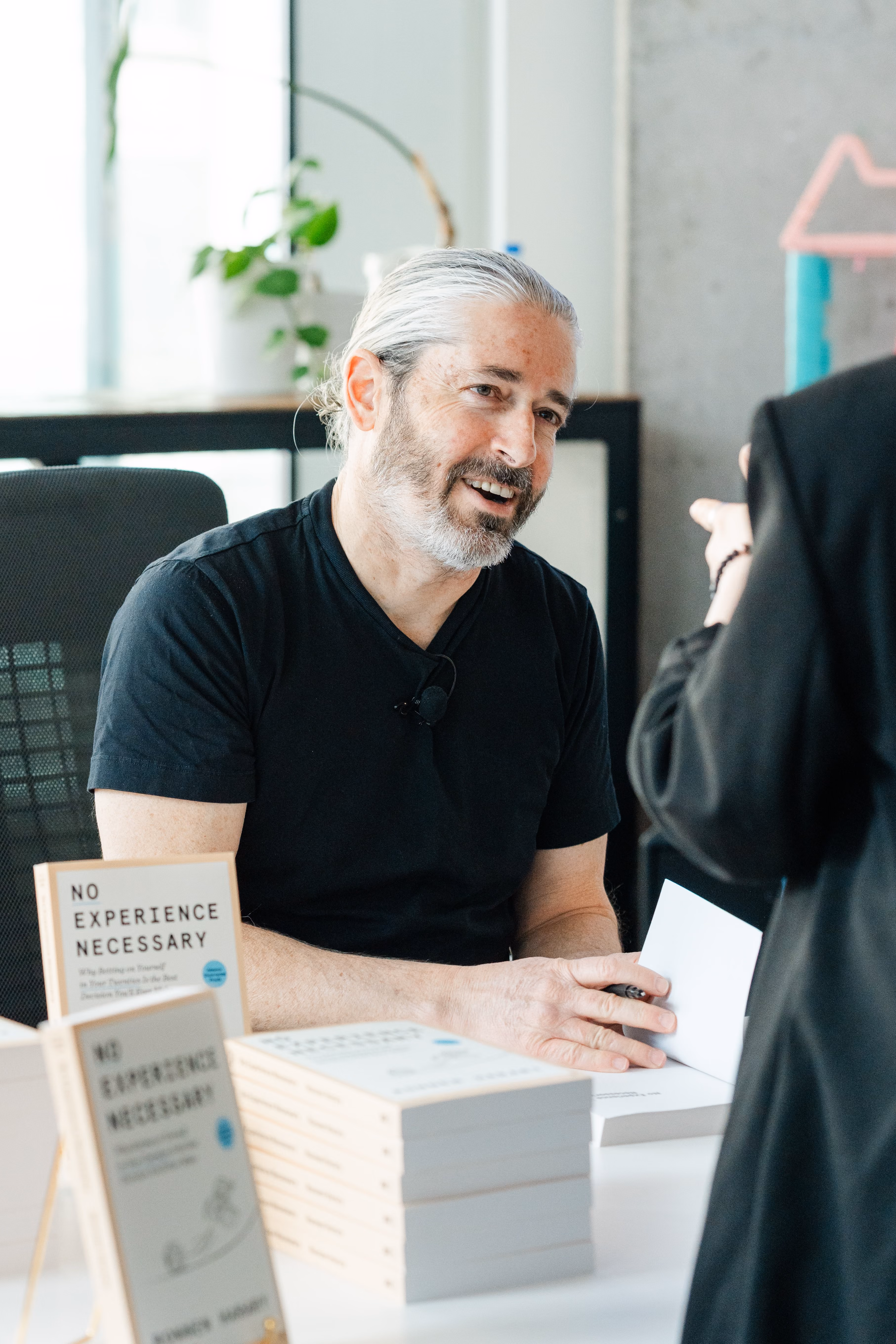 Ronnen signing his book titled 'No Experience Necessary' at a table.