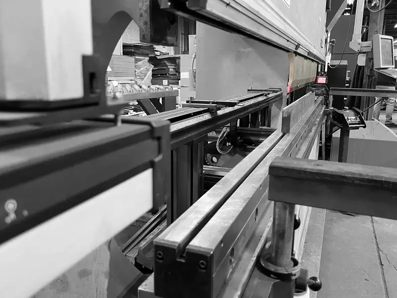 Close-up view of industrial metalworking machinery with metal beams and control panels in a factory setting.