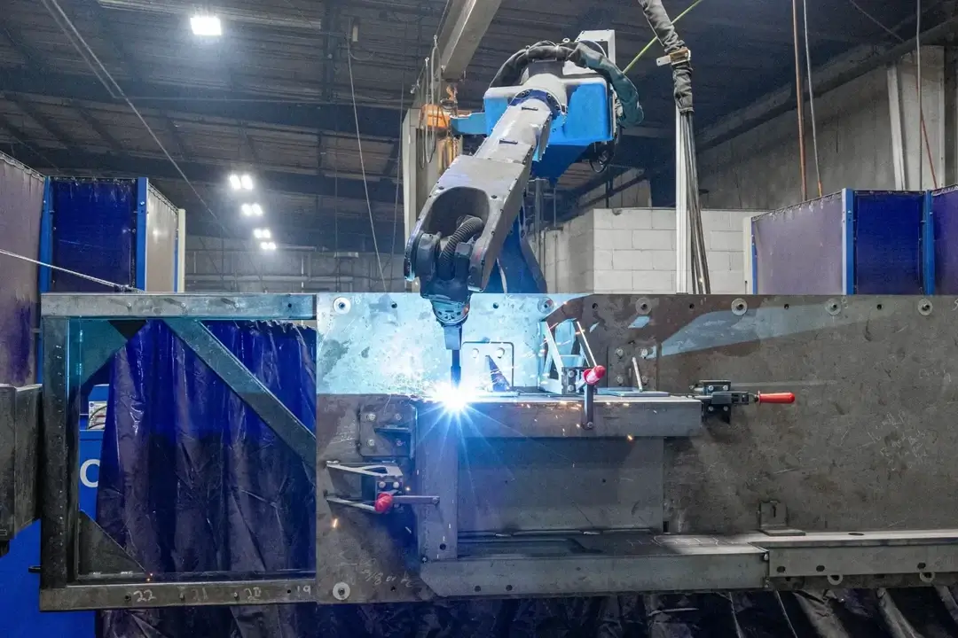 Yaskawa YRC1000 + AR-Series Robot performing welding on a large metal structure inside a factory.