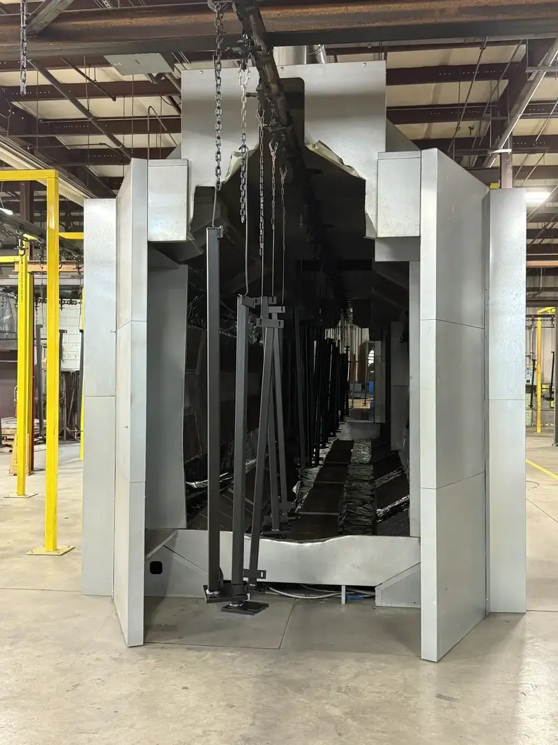 Hanging metal parts moving through an infrared oven to cure powder coat.