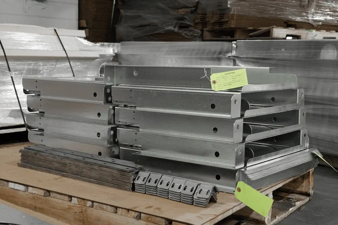 Stacked metal components on a pallet with inspection tags, ready for shipment or assembly.