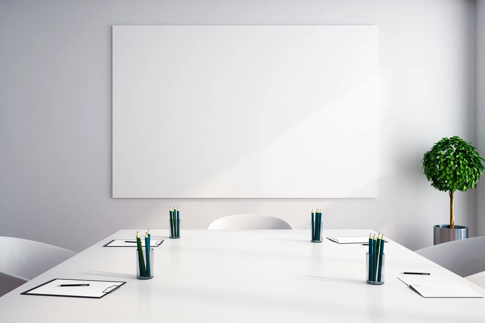 Minimalist white conference room with a large white table, green pencils in glass holders, clipboards with pens, a blank whiteboard on the wall, and a potted plant in the corner.