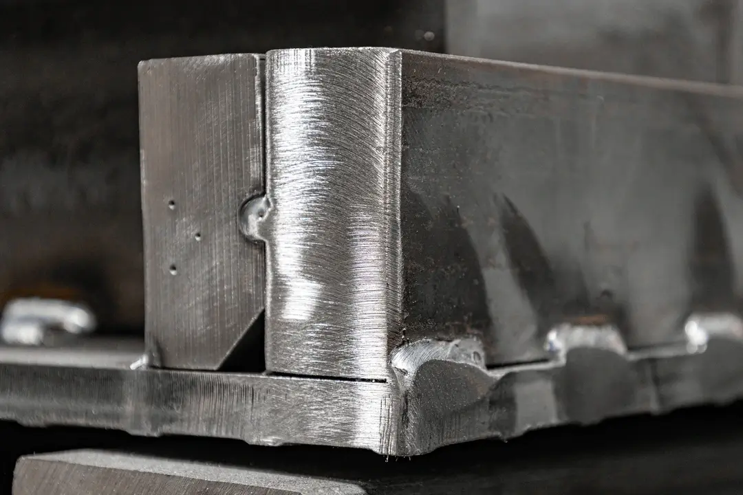Close-up of a welded metal corner joint with visible weld beads and polished surfaces.