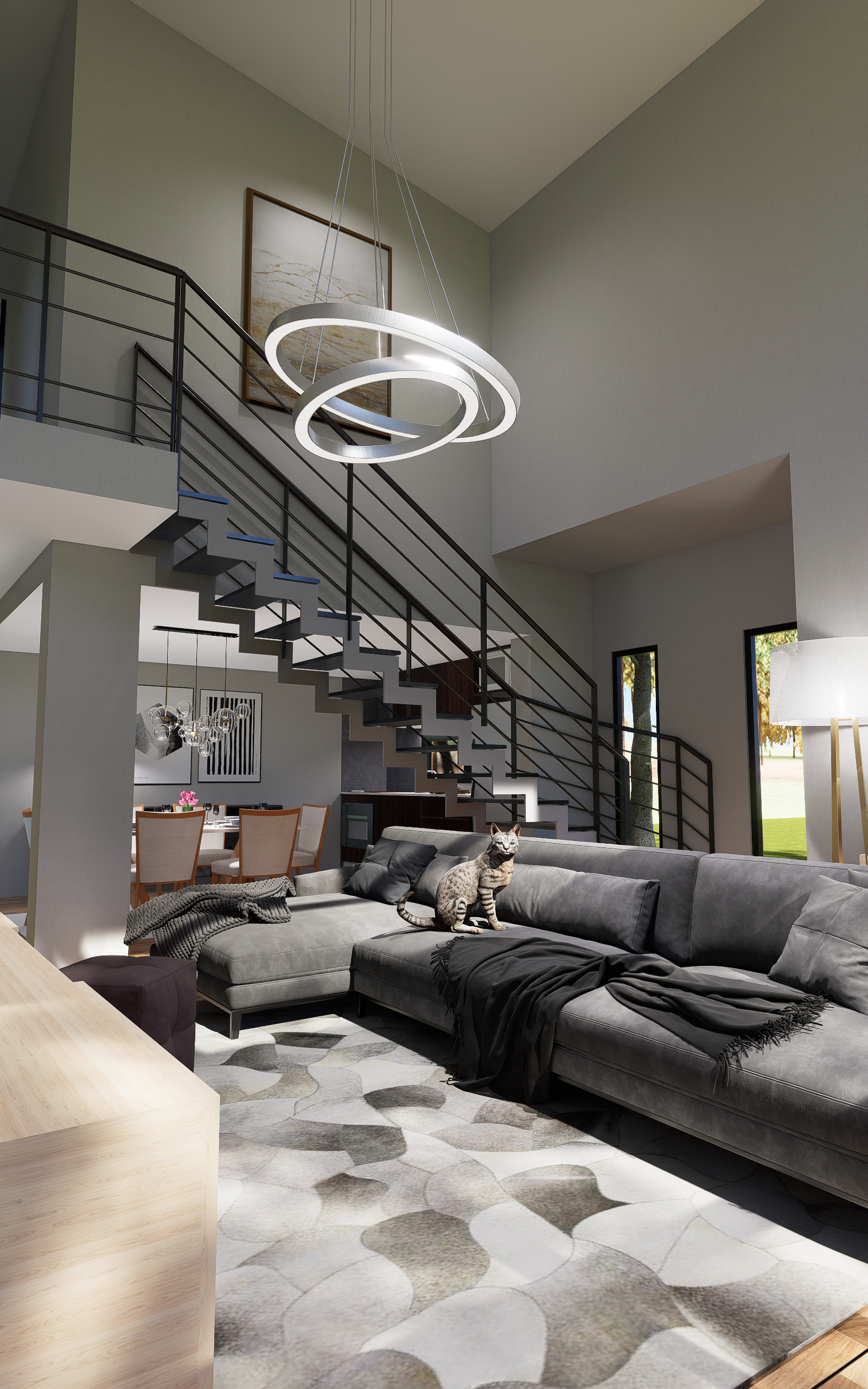Modern living room with gray sectional sofa, black throw, circular pendant light, and a cat sitting on the sofa by the staircase.