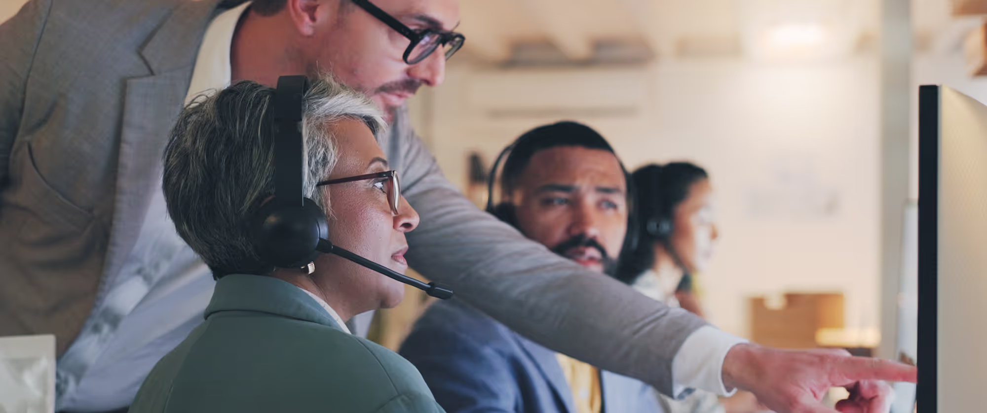 Full indoor shot of a group of people, working in a customer service or call center environment.