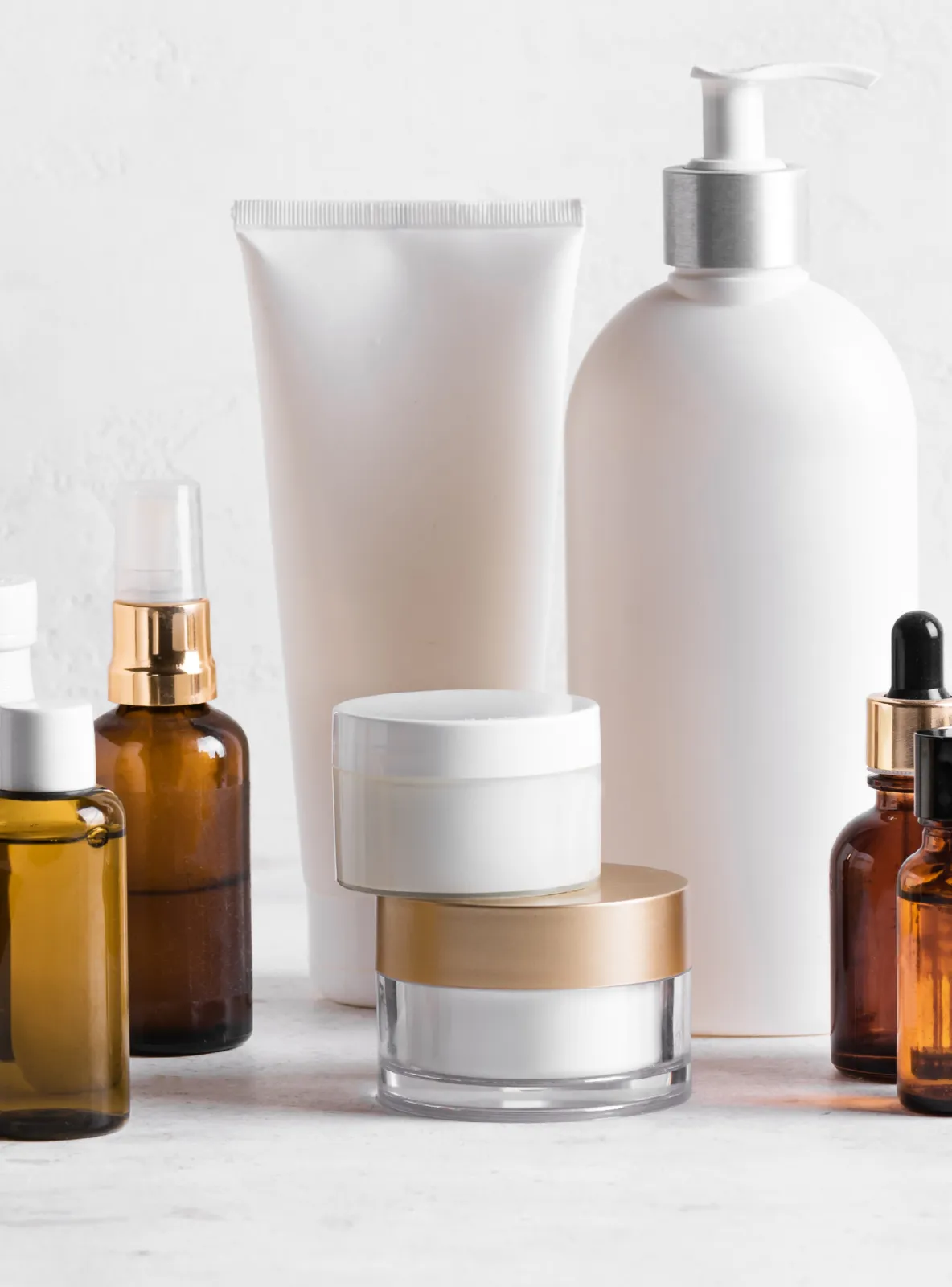 Unbranded personal care packaging: white tube, pump bottle, cream jars and amber serum bottles