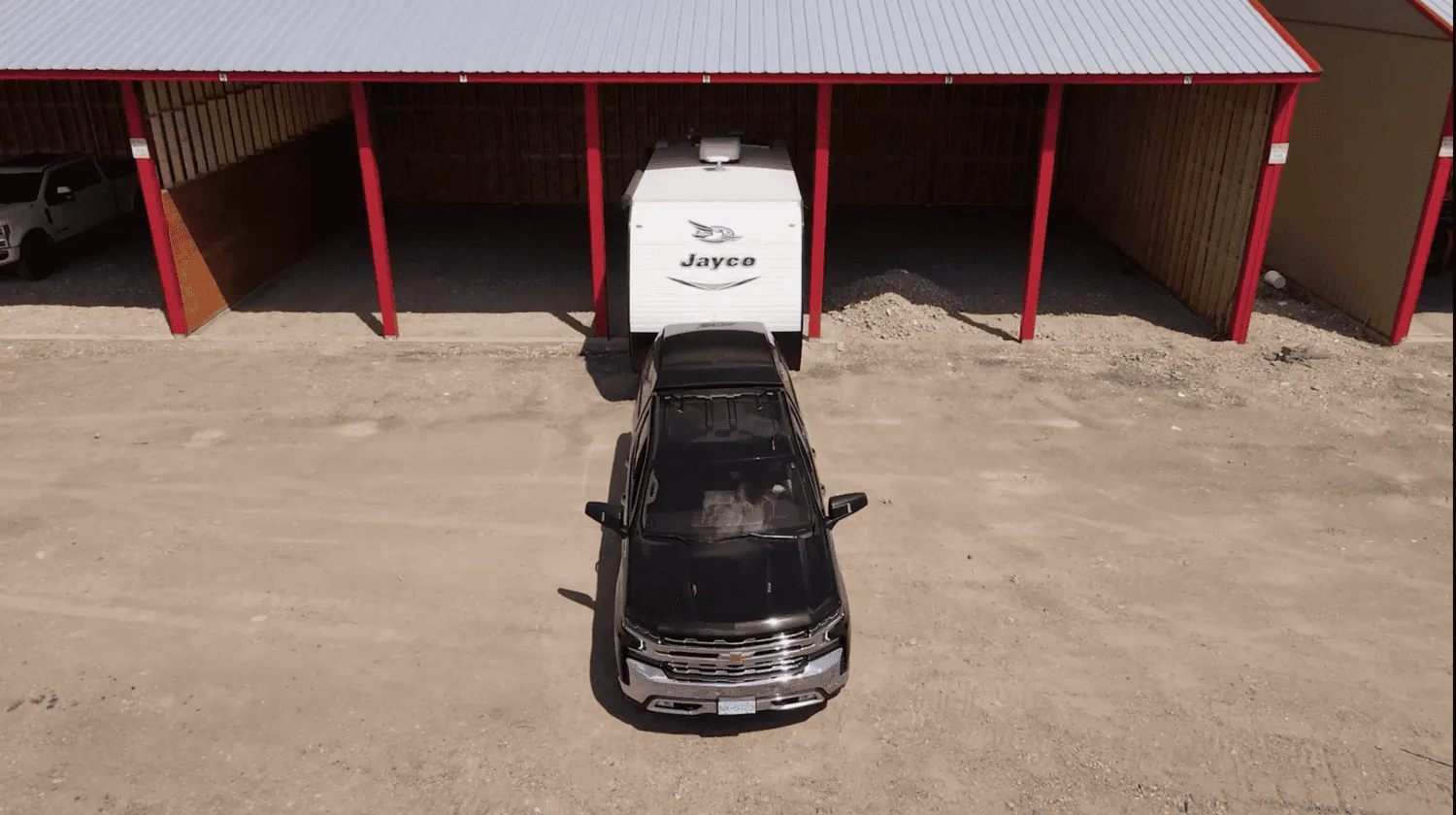 Black truck backing RV into an RV storage